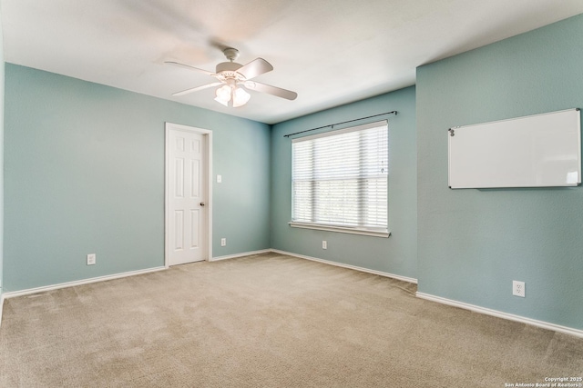carpeted spare room featuring a ceiling fan and baseboards