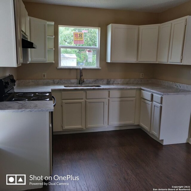 kitchen featuring white cabinets, a sink, dark wood-style floors, and black / electric stove