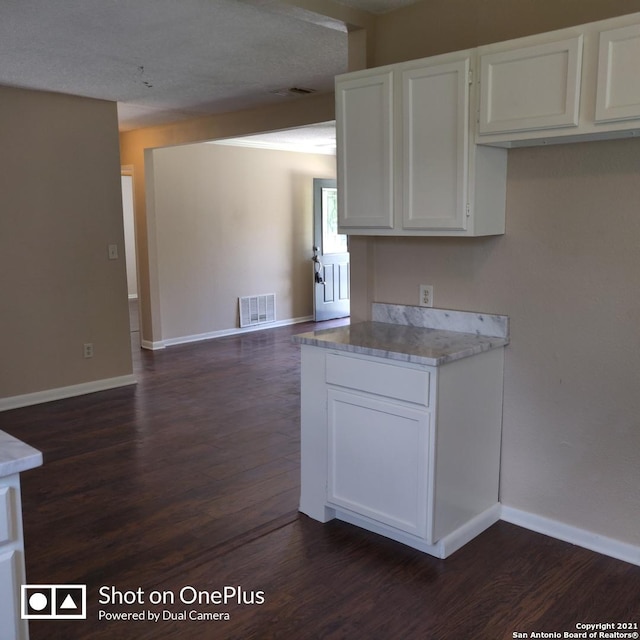 kitchen featuring white cabinets, visible vents, light countertops, baseboards, and dark wood-style floors