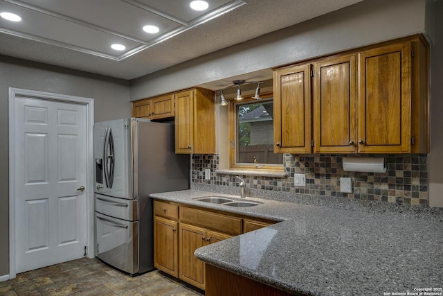 kitchen featuring a sink, stainless steel refrigerator with ice dispenser, tasteful backsplash, and brown cabinets