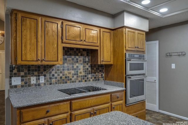 kitchen with black electric stovetop, double oven, brown cabinets, tasteful backsplash, and recessed lighting