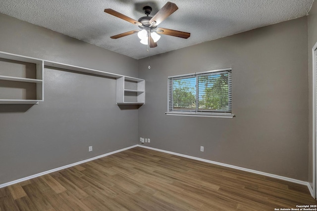 spare room featuring ceiling fan, wood finished floors, a textured ceiling, and baseboards