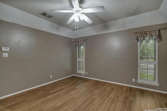 unfurnished room featuring wood finished floors, a ceiling fan, a textured ceiling, and baseboards