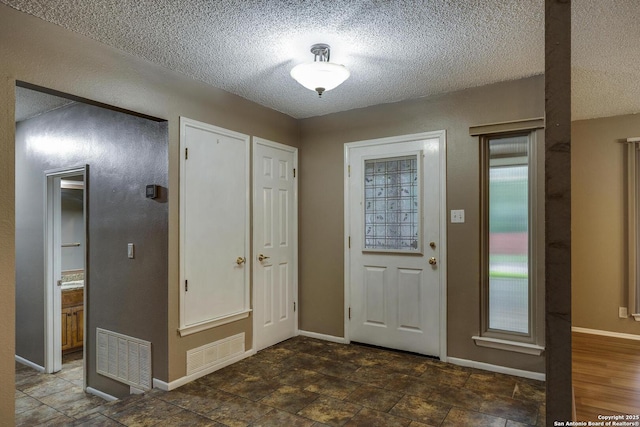 foyer entrance with a textured ceiling and baseboards