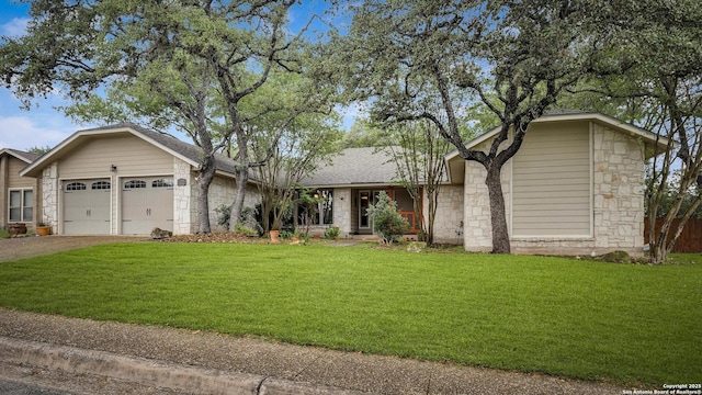 ranch-style home featuring stone siding, a garage, a front lawn, and driveway