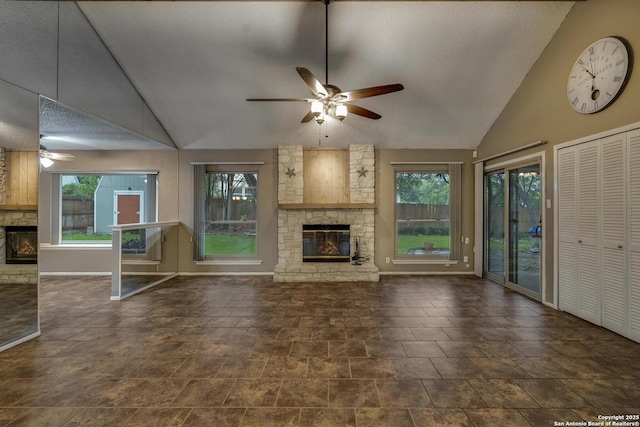 unfurnished living room featuring a stone fireplace, a ceiling fan, vaulted ceiling, baseboards, and a textured ceiling