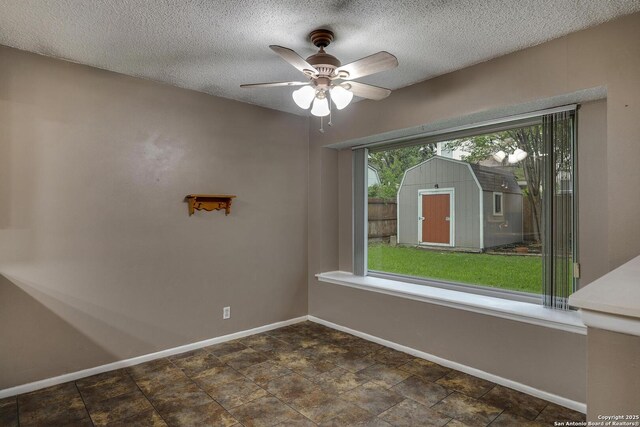 spare room featuring baseboards, ceiling fan, and a textured ceiling