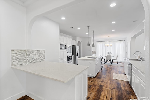 19211 Tierra Cv, San Antonio, TX 78258 - kitchen with a peninsula, a center island, stainless steel appliances, arched walkways, and a sink