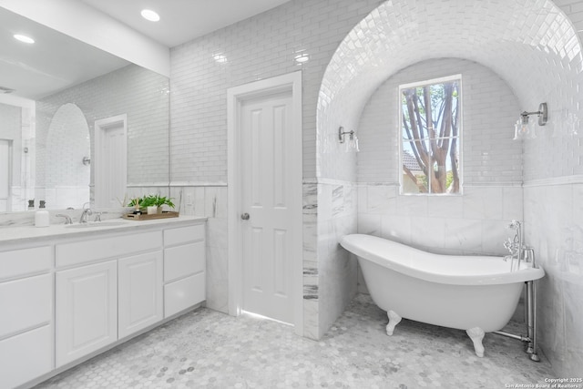 19211 Tierra Cv, San Antonio, TX 78258 - full bath with visible vents, tile walls, a soaking tub, vanity, and a wainscoted wall