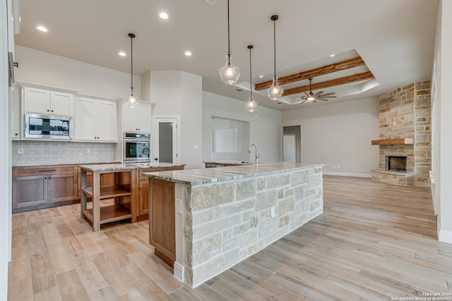 200 Bobby Lynn, Adkins, TX 78101 - kitchen with a fireplace, a large island with sink, open shelves, stainless steel microwave, and backsplash
