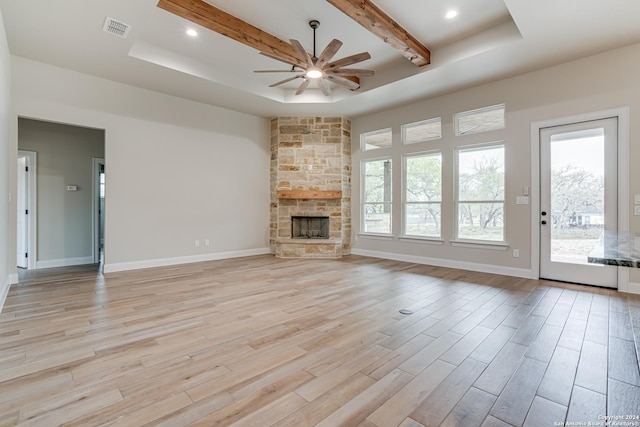200 Bobby Lynn, Adkins, TX 78101 - unfurnished living room with a fireplace, light wood-style flooring, visible vents, a tray ceiling, and ceiling fan