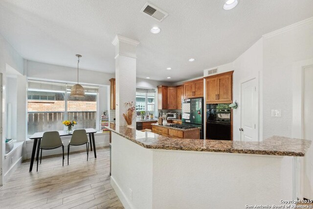 2047 Thicket Trail Dr, San Antonio, TX 78248 - kitchen featuring dark stone counters, brown cabinetry, ornate columns, visible vents, and a kitchen island