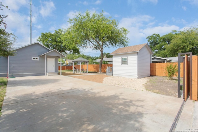 view of patio / terrace featuring an outbuilding, a gazebo, fence, and concrete driveway