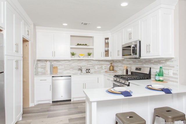 kitchen with visible vents, open shelves, a sink, a peninsula, and stainless steel appliances