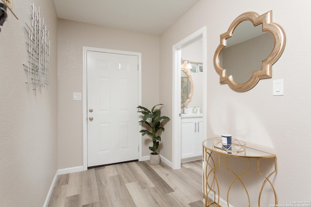 foyer entrance with light wood-style flooring and baseboards