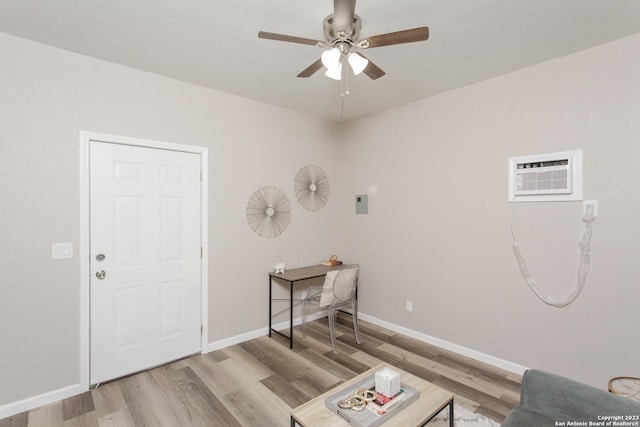 interior space with an AC wall unit, ceiling fan, light wood-style floors, and baseboards
