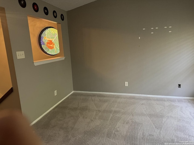 carpeted empty room featuring baseboards