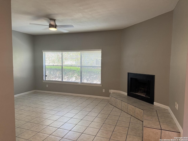unfurnished living room with a fireplace with raised hearth, baseboards, light tile patterned flooring, and ceiling fan