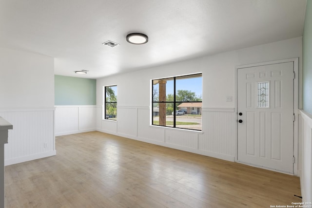 foyer with visible vents, a wainscoted wall, and wood finished floors