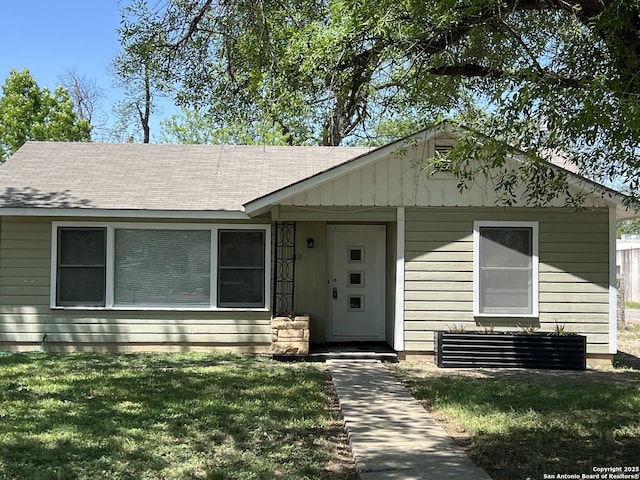 view of front of house with a shingled roof and a front lawn