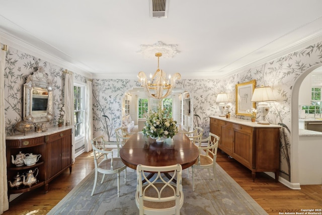 643 Terrell Rd, Terrell Hills, TX 78209 - dining room featuring wallpapered walls, arched walkways, a chandelier, wood finished floors, and crown molding