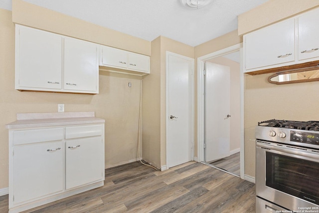 kitchen featuring light wood finished floors, light countertops, white cabinets, baseboards, and stainless steel range with gas stovetop