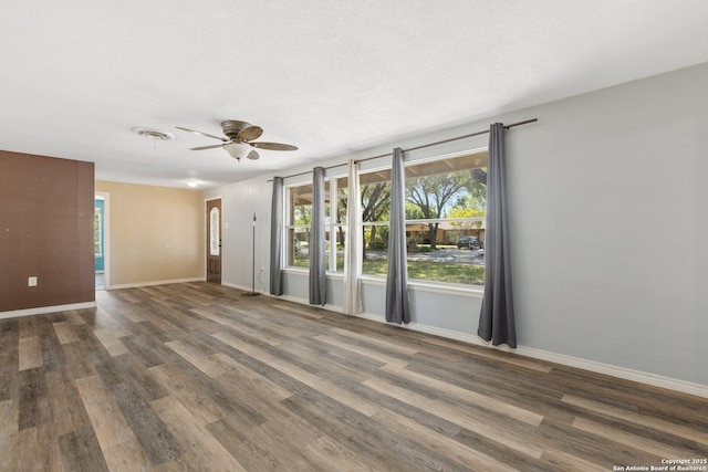empty room featuring baseboards, a ceiling fan, and wood finished floors