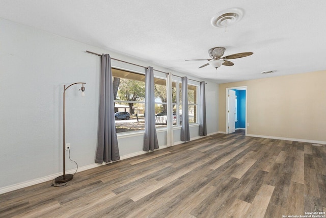 empty room featuring wood finished floors, baseboards, and ceiling fan