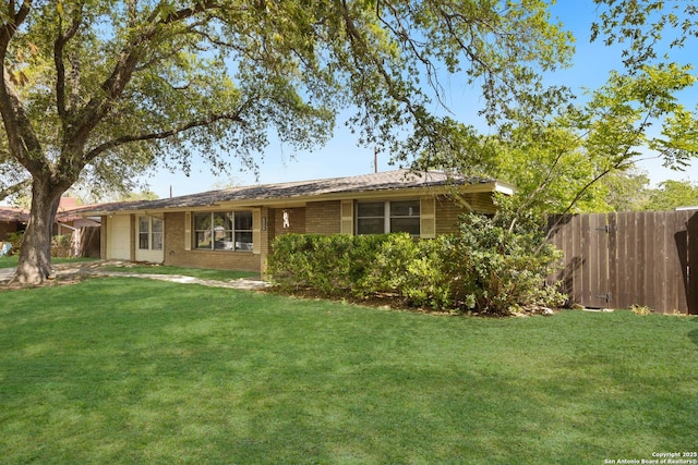 back of property featuring brick siding, fence, and a yard