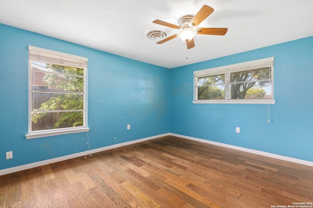 empty room with ceiling fan, baseboards, wood finished floors, and visible vents