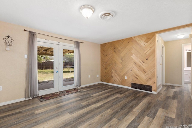 spare room featuring wooden walls, wood finished floors, baseboards, and french doors