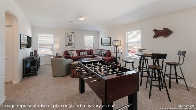 rec room with arched walkways, a wealth of natural light, carpet flooring, and baseboards