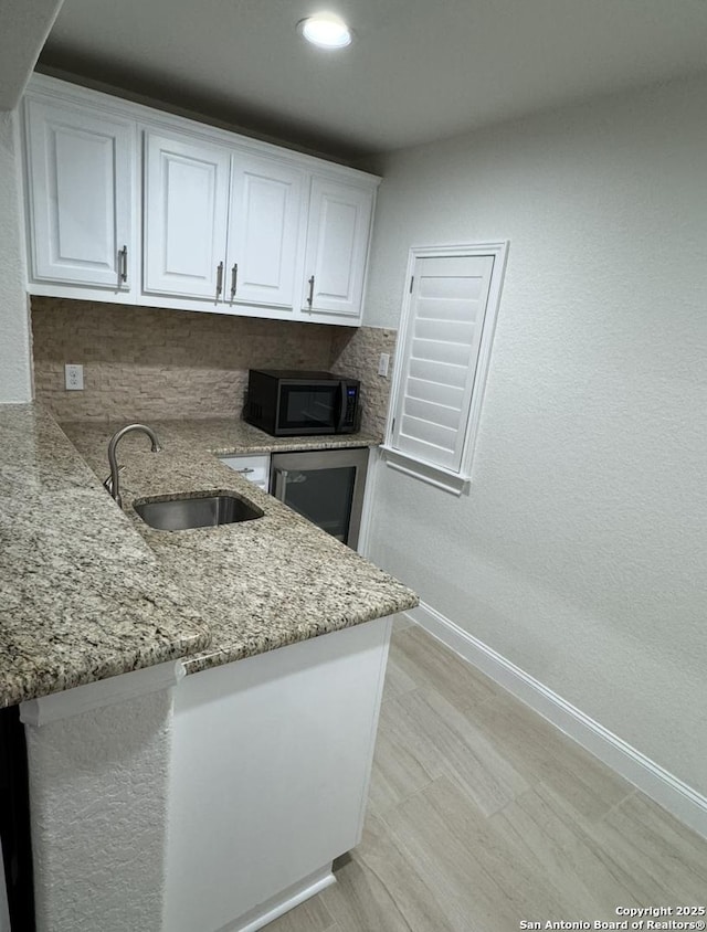 8118 Vanity, San Antonio, TX 78256 - kitchen featuring baseboards, white cabinets, a sink, black microwave, and light stone counters