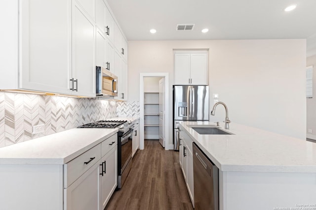 kitchen with visible vents, a sink, dark wood-style floors, a center island with sink, and stainless steel appliances