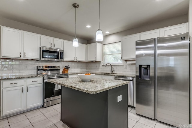 kitchen featuring appliances with stainless steel finishes, light tile patterned floors, a sink, and a kitchen island