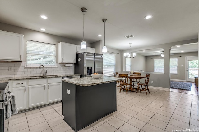 kitchen featuring light tile patterned floors, visible vents, a sink, stainless steel fridge, and decorative backsplash