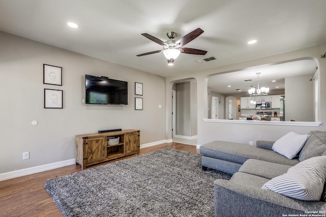 living room with baseboards, visible vents, arched walkways, ceiling fan with notable chandelier, and wood finished floors