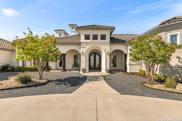 view of front of home with french doors, a tiled roof, and stucco siding