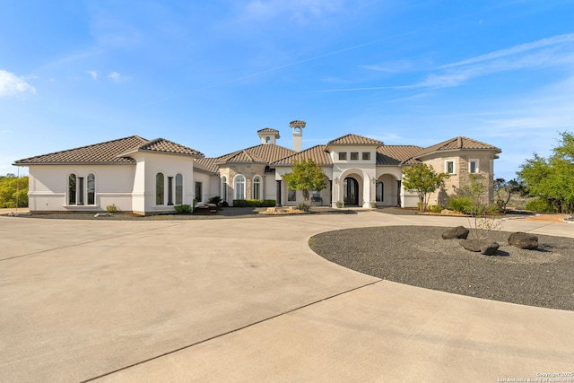 mediterranean / spanish-style house with curved driveway, stucco siding, and a tile roof
