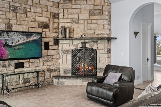 living room featuring arched walkways, a fireplace, and tile patterned floors