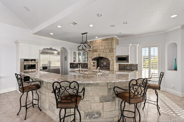 kitchen featuring visible vents, built in appliances, a kitchen bar, and light tile patterned flooring