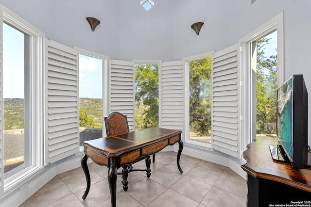 office area featuring light tile patterned floors, baseboards, a wealth of natural light, and a towering ceiling