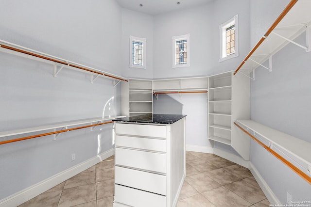 walk in closet with light tile patterned floors and a high ceiling