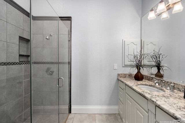 full bath featuring tile patterned floors, baseboards, a shower stall, and vanity