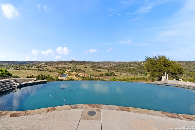 view of swimming pool with an infinity pool and a patio