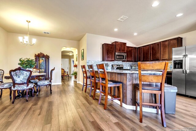 8926 Double Oak, San Antonio, TX 78254 - kitchen with light wood-style floors, visible vents, decorative backsplash, arched walkways, and appliances with stainless steel finishes