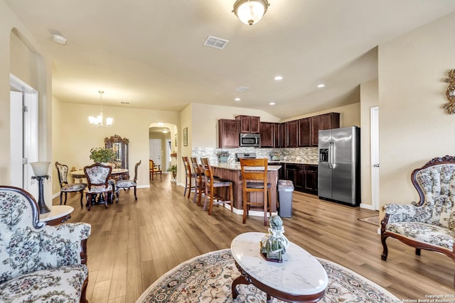 8926 Double Oak, San Antonio, TX 78254 - living room featuring an inviting chandelier, light wood-style flooring, arched walkways, vaulted ceiling, and visible vents