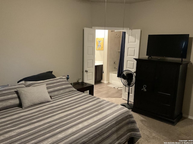 bedroom featuring ensuite bath and baseboards