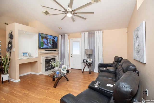 8418 Hera, Universal City, TX 78148 - living room featuring light wood-style floors, a glass covered fireplace, vaulted ceiling, a ceiling fan, and visible vents