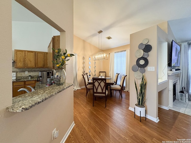 8418 Hera, Universal City, TX 78148 - dining room with a fireplace, visible vents, a chandelier, wood finished floors, and baseboards